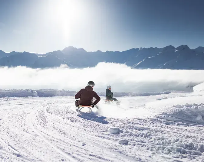 Two sledges picking up speed on the prepared night toboggan track